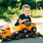 A joyful child playing with a toy bulldozer truck on a sunny day outdoors, enjoying playtime.